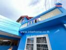 Brightly colored blue exterior of a building with visible windows and balcony