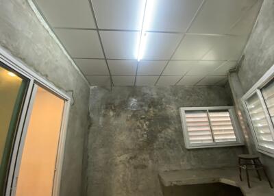 A simple unfinished room with concrete walls and a fluorescent ceiling light