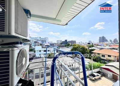 View from a balcony with visible air conditioning units and a cityscape in the background