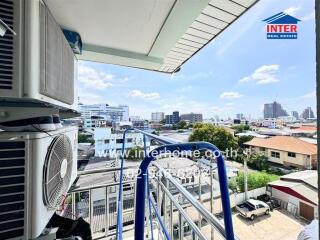 View from a balcony with visible air conditioning units and a cityscape in the background