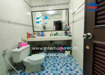 Bathroom with blue tile flooring, large mirror, and various toiletries