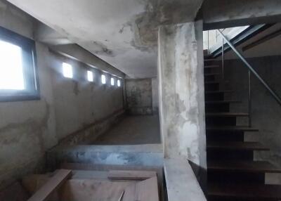 Unfinished basement with small windows and partially constructed staircase