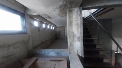 Unfinished basement with small windows and partially constructed staircase