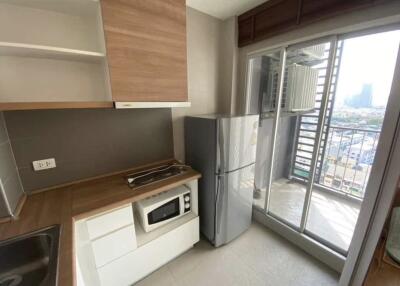 A modern kitchen with a fridge, microwave, stove, and ample cabinets, adjacent to a balcony.