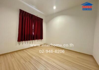 Spacious empty bedroom with red curtains and wooden floor