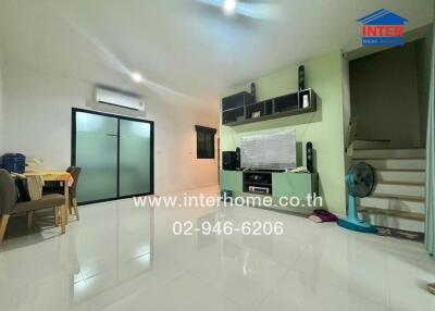 Spacious and modern living room featuring a dining area, entertainment center, and stairs leading to the upper floor