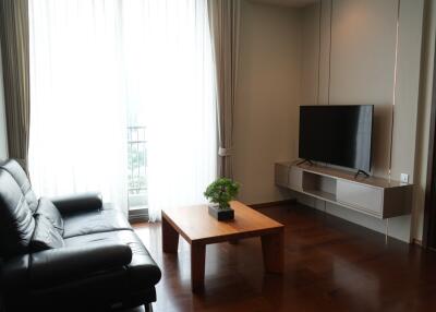 Modern living room with black leather sofa, wooden coffee table, and wall-mounted TV