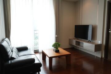 Modern living room with black leather sofa, wooden coffee table, and wall-mounted TV