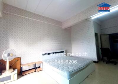 Unfurnished bedroom with a bed, nightstand, and electric fan