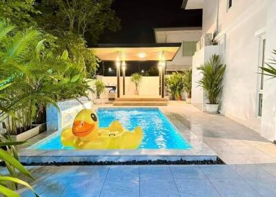 Outdoor swimming pool with inflatable duck and surrounding greenery