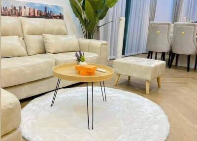 Modern living room with a white sofa, round coffee table, and dining area in the background.