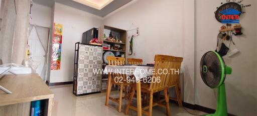 dining area with wooden chairs and table, refrigerator, and a corner shelf