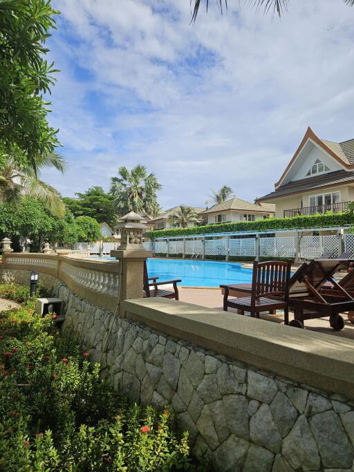 Swimming pool area with seating and surrounding houses