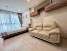 Modern living area with a beige sofa, bed, and large windows