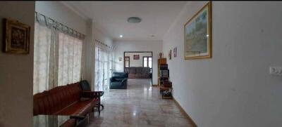 Main living space with seating area, wall decor, and large windows with sheer curtains