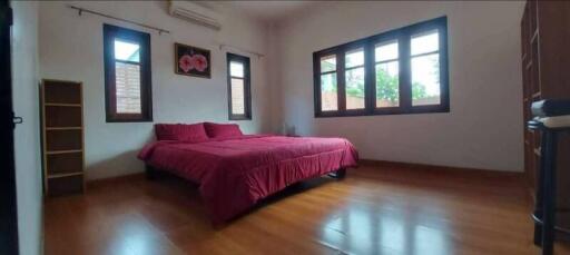 Bedroom with wooden floor, large windows, and red bedding