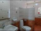 Bathroom with white sink, toilet, and wall tiles