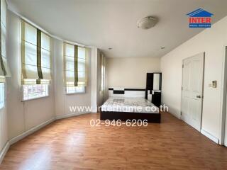 Bedroom with wooden flooring and multiple windows