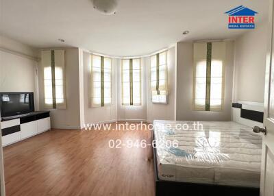 Spacious bedroom with hardwood floors, large windows, and a bed