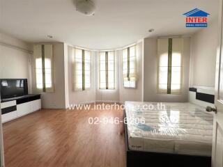 Spacious bedroom with hardwood floors, large windows, and a bed