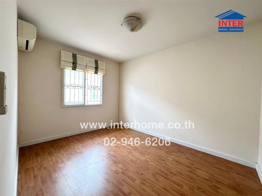 Spacious bedroom with wooden flooring and a window with blinds