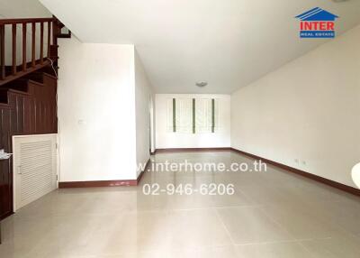 Spacious empty living room with staircase and white walls