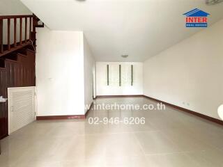 Spacious empty living room with staircase and white walls