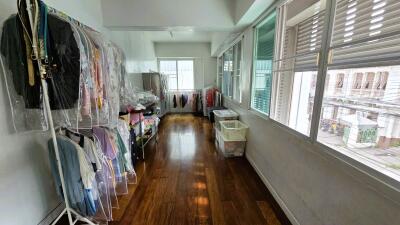 A bright storage room with clothes and plastic bins.