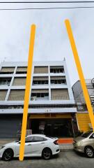 Front view of a multi-story building with cars parked in front