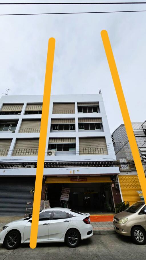 Front view of a multi-story building with cars parked in front