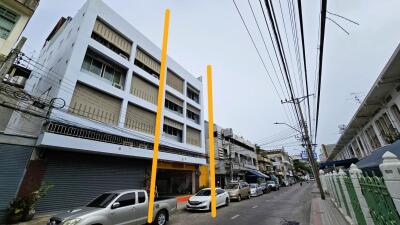 Street view of a multi-story building with parked cars