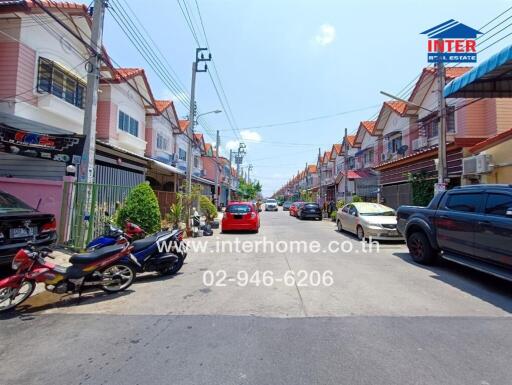 Street view of residential area with parked cars and motorbikes
