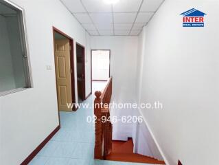 Hallway with stairway, doorways, and visible natural light