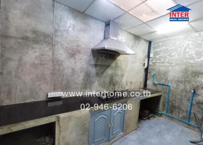 A kitchen with concrete walls, sink, and ventilation hood