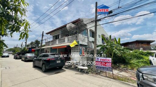 Two-story residential building with cars parked in front and signage