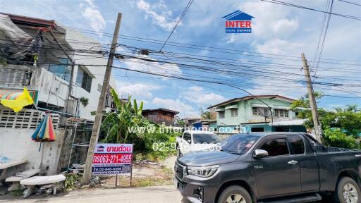 View of the exterior surroundings of the property featuring nearby houses, vegetation, and street with parked vehicle