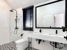 Modern bathroom with black and white geometric tile floor, dual sinks, large mirror, and walk-in shower