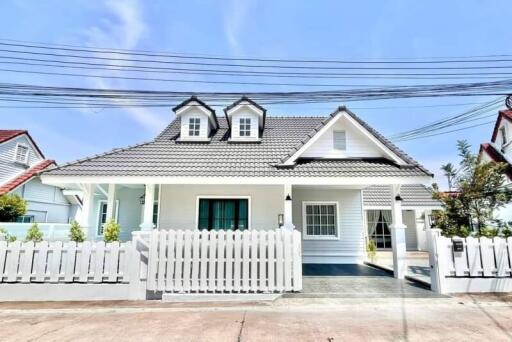 Front view of a modern suburban house with a white picket fence