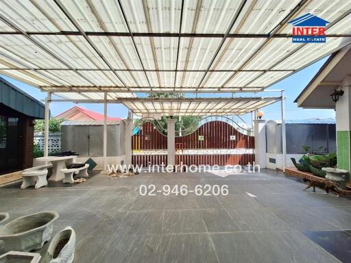 Spacious covered patio area with stone furniture and decorative gate