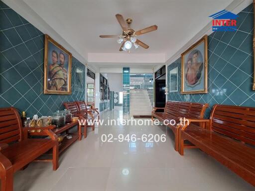 Main entrance hall with wooden benches, blue-tiled walls, and ceiling fan