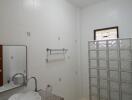 Modern bathroom with a sink, toilet, and glass block partition