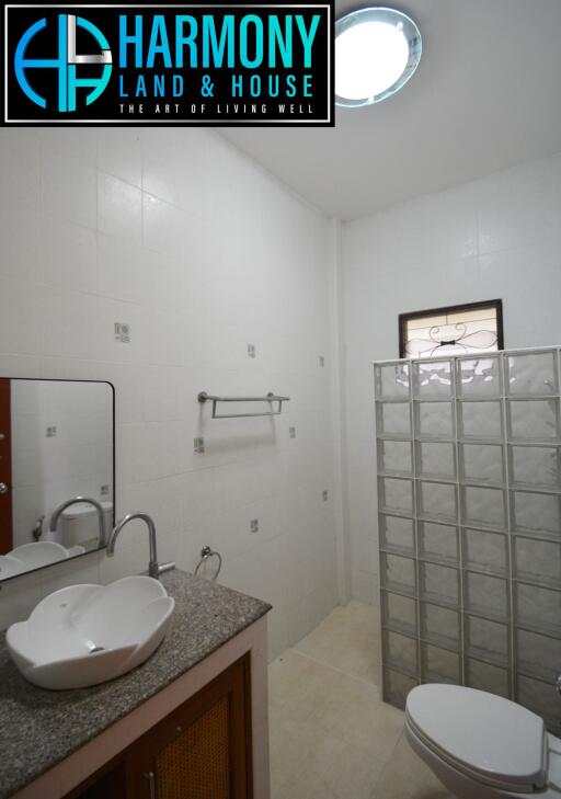 Modern bathroom with a sink, toilet, and glass block partition