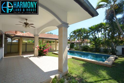 Covered patio area with ceiling fan overlooking landscaped garden and pool