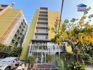 Front view of the apartment building with surrounding greenery and parking area