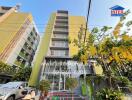 Front view of the apartment building with surrounding greenery and parking area