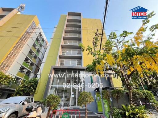 Front view of the apartment building with surrounding greenery and parking area