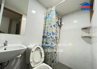 White-tiled bathroom with shower, toilet, and sink