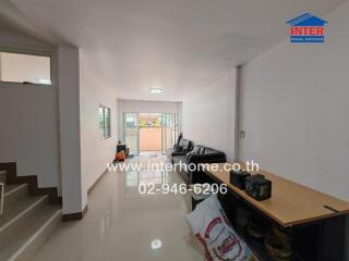 Living room with tiled flooring, a black leather sofa, and a small office area