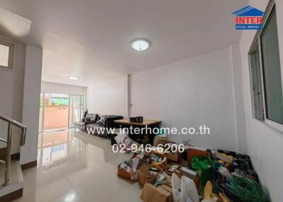 Living room with minimal furniture and boxes, reflective floor, and bright lighting