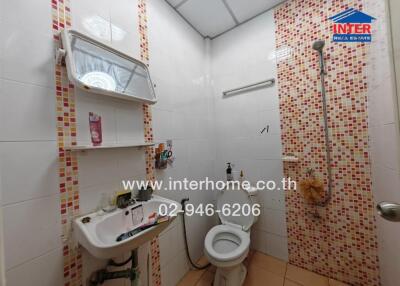 Bathroom with shower, toilet, sink, and tiled walls